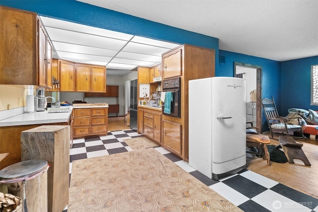 9139 Burnett Rd SE, Yelm, WA 98597 - kitchen with light floors, freestanding refrigerator, black oven, light countertops, and brown cabinets