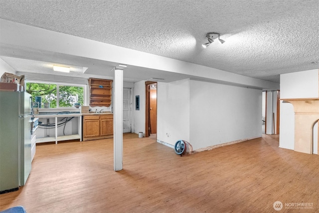 9139 Burnett Rd SE, Yelm, WA 98597 - basement with freestanding refrigerator, light wood-type flooring, and a textured ceiling