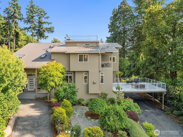 6819 SE 32nd St, Mercer Island, WA 98040 - view of front of house featuring stucco siding, a standing seam roof, metal roof, driveway, and a balcony