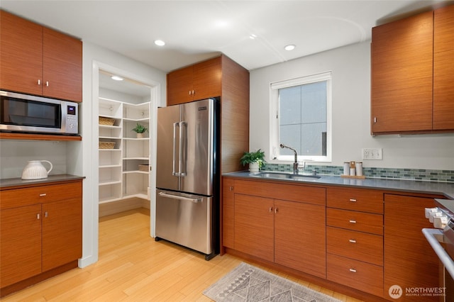 1805 N 36th St, Seattle, WA 98103 - kitchen with stainless steel appliances, light wood-style flooring, a sink, dark countertops, and brown cabinets