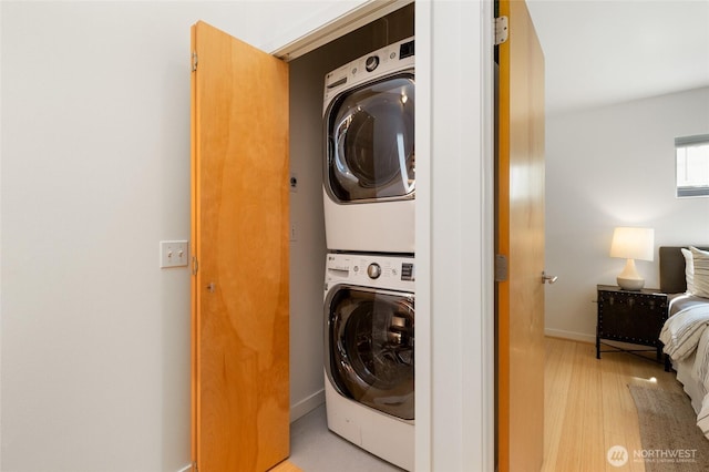 1805 N 36th St, Seattle, WA 98103 - washroom with estacked washer and dryer, light wood-style floors, and baseboards