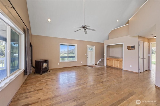 42480 N State Route 25, Davenport, WA 99122 - unfurnished living room with a wood stove, plenty of natural light, light wood-style flooring, high vaulted ceiling, and baseboards