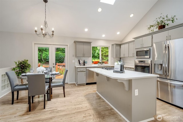 10411 23rd Street Ct E, Edgewood, WA 98372 - kitchen featuring appliances with stainless steel finishes, gray cabinetry, a center island, vaulted ceiling, and light countertops