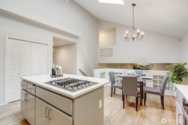 10411 23rd Street Ct E, Edgewood, WA 98372 - kitchen with stainless steel gas stovetop, light wood-type flooring, light countertops, a chandelier, and high vaulted ceiling