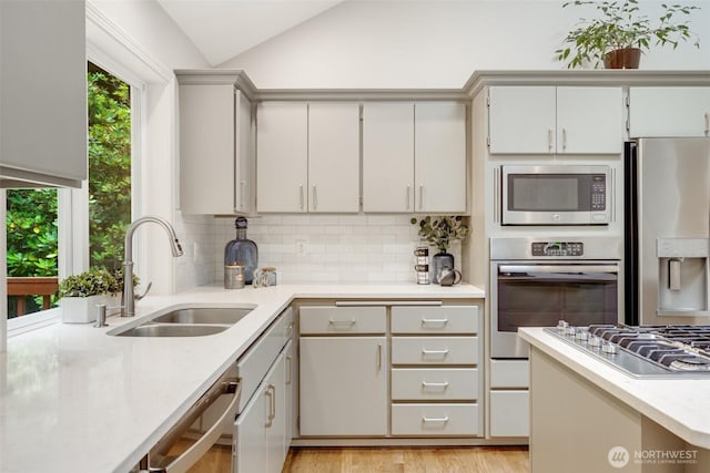 10411 23rd Street Ct E, Edgewood, WA 98372 - kitchen featuring stainless steel appliances, vaulted ceiling, tasteful backsplash, light countertops, and light wood-style flooring