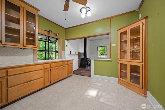 500 Wilson Ave, Bellingham, WA 98225 - kitchen featuring a wood stove, light countertops, a ceiling fan, crown molding, and glass insert cabinets