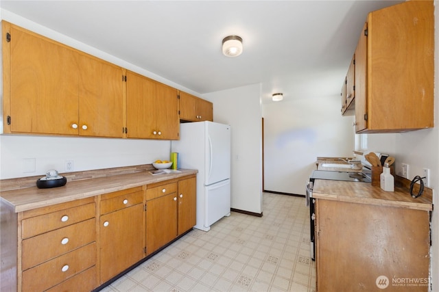 3309 W 2nd St, Anacortes, WA 98221 - kitchen featuring stainless steel electric stove, freestanding refrigerator, light flooring, light countertops, and baseboards