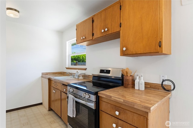 3309 W 2nd St, Anacortes, WA 98221 - kitchen with stainless steel electric range, a sink, light flooring, baseboards, and brown cabinetry