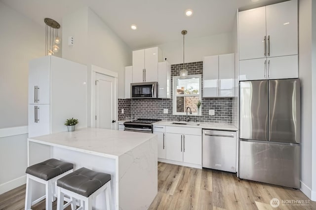 1808 S Raymond St, Seattle, WA 98108 - kitchen with appliances with stainless steel finishes, a sink, decorative backsplash, white cabinets, and light wood finished floors