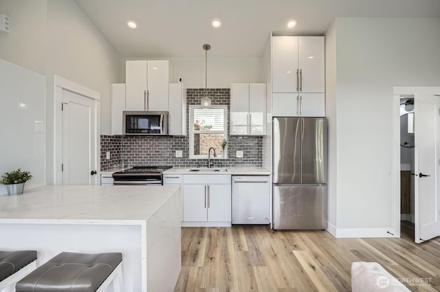 1808 S Raymond St, Seattle, WA 98108 - kitchen with stainless steel appliances, white cabinetry, light wood finished floors, a sink, and tasteful backsplash