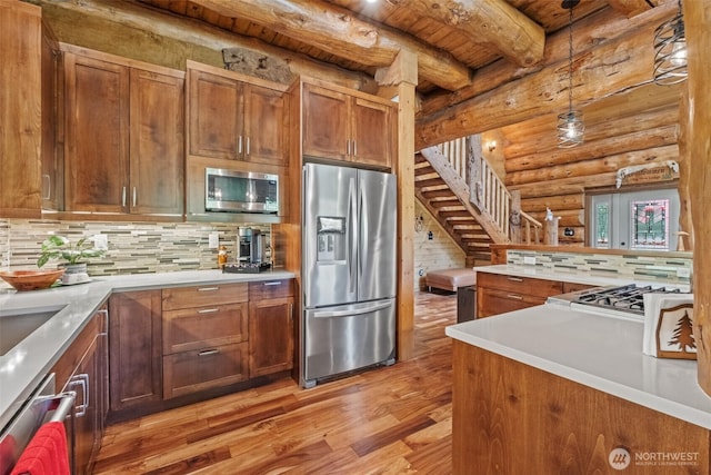 158 Big Pine Dr, Leavenworth, WA 98826 - kitchen featuring stainless steel appliances, log walls, light wood-style flooring, brown cabinetry, and hanging light fixtures
