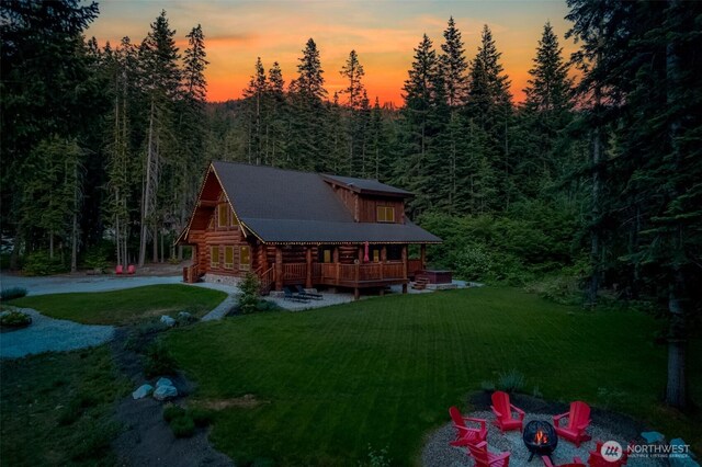 158 Big Pine Dr, Leavenworth, WA 98826 - back of house with log exterior, an outdoor fire pit, a yard, a view of trees, and a garage