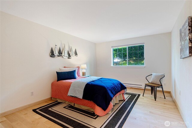 215 9th St Unit D101, Kirkland, WA 98033 - bedroom featuring a baseboard heating unit, light wood-style flooring, and baseboards