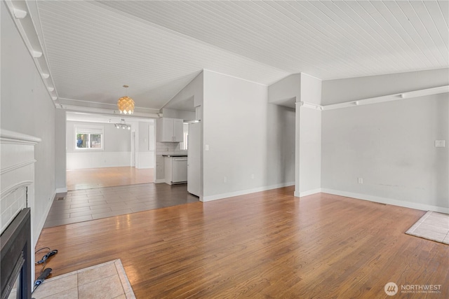 17004 11th Ave NE, Shoreline, WA 98155 - unfurnished living room featuring a tiled fireplace, wood finished floors, and baseboards