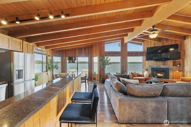 6570 E Grapeview Loop Rd, Allyn, WA 98524 - living room with wood finished floors, wood ceiling, a warm lit fireplace, wood walls, and a ceiling fan