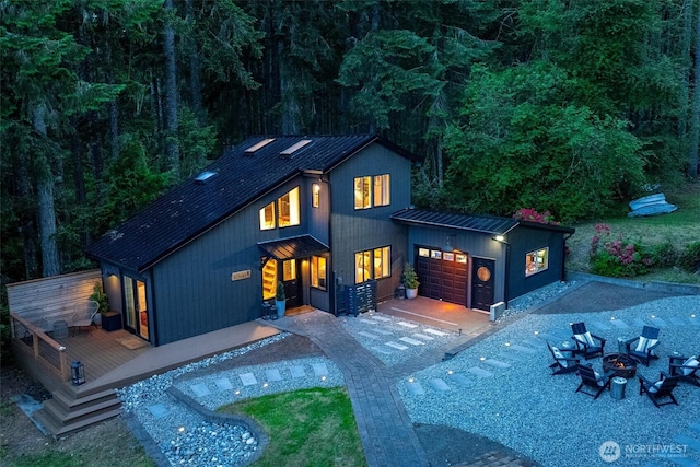 6570 E Grapeview Loop Rd, Allyn, WA 98524 - rear view of property featuring an outdoor fire pit, metal roof, a standing seam roof, a garage, and a deck