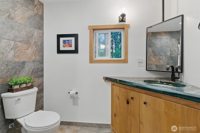 6570 E Grapeview Loop Rd, Allyn, WA 98524 - bathroom featuring toilet, vanity, baseboards, and tile walls