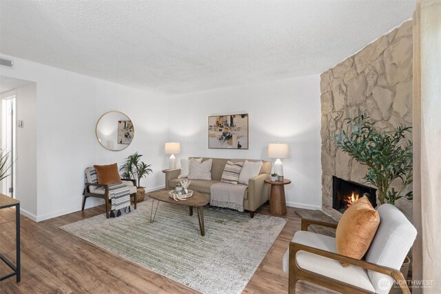 12515 NE 145th Pl Unit D121, Kirkland, WA 98034 - living area featuring a stone fireplace, a textured ceiling, wood finished floors, and baseboards