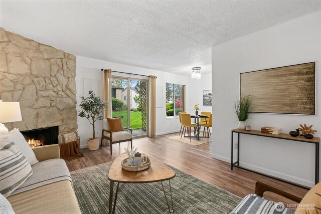 12515 NE 145th Pl Unit D121, Kirkland, WA 98034 - living room with a textured ceiling, wood finished floors, a stone fireplace, and baseboards