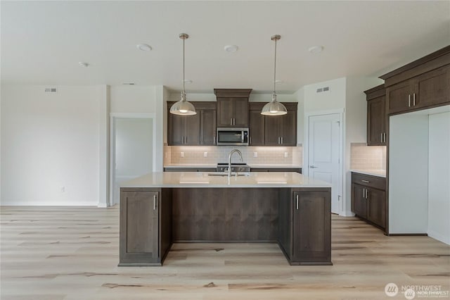 603 Cardinal Ave, Winlock, WA 98596 - kitchen with stainless steel microwave, light wood finished floors, light countertops, dark brown cabinets, and backsplash