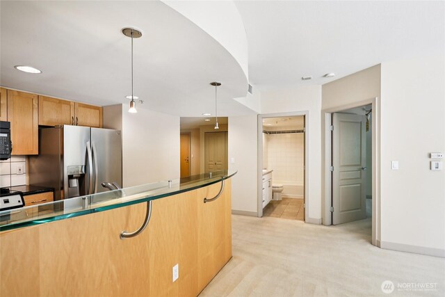 2929 1st Ave Unit 205, Seattle, WA 98121 - kitchen with stainless steel fridge, hanging light fixtures, dark countertops, and recessed lighting