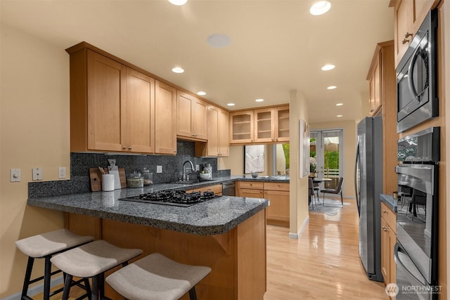 740 1st St S, Kirkland, WA 98033 - kitchen featuring stainless steel appliances, a peninsula, backsplash, light wood finished floors, and a breakfast bar area