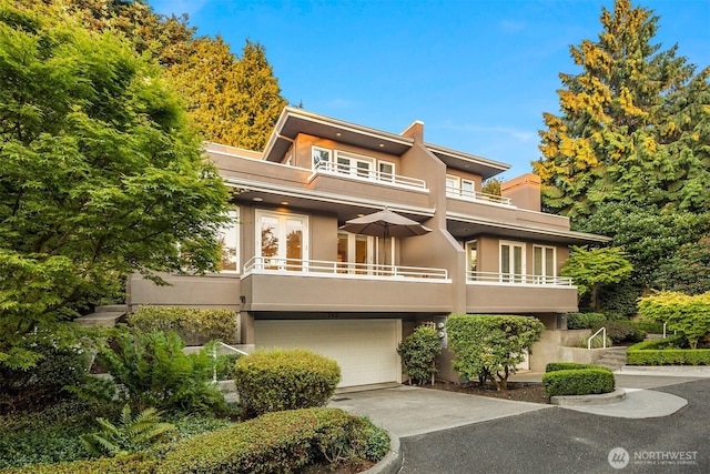 740 1st St S, Kirkland, WA 98033 - view of front facade featuring a balcony, stucco siding, a garage, driveway, and french doors