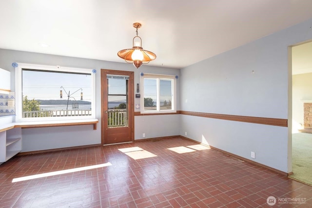 1001 S 226th St, Des Moines, WA 98198 - unfurnished dining area featuring brick patterned flooring, baseboards, and healthy amount of natural light