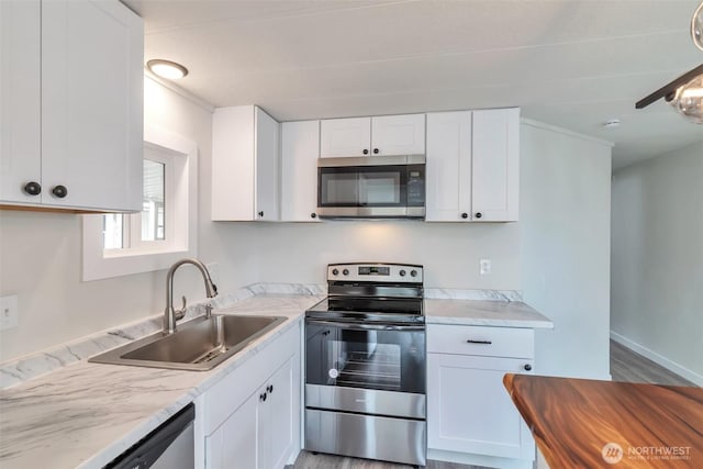 18501 52nd Ave W Unit 84, Lynnwood, WA 98037 - kitchen featuring appliances with stainless steel finishes, a sink, white cabinets, light wood-type flooring, and light stone counters