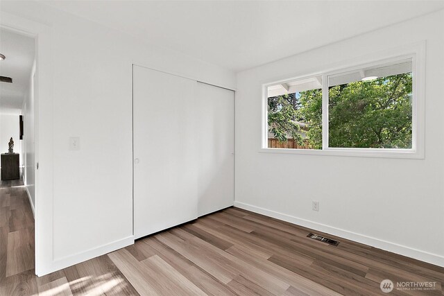 25035 34th Ave S, Kent, WA 98032 - unfurnished bedroom featuring multiple windows, wood finished floors, and a closet