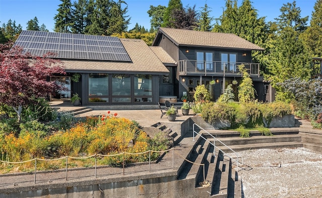9707 SW Quartermaster Dr, Vashon, WA 98070 - back of house with roof mounted solar panels, a balcony, roof with shingles, and a patio