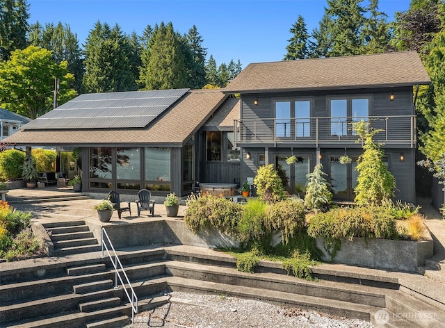 9707 SW Quartermaster Dr, Vashon, WA 98070 - rear view of house with solar panels, a shingled roof, a balcony, a patio, and a hot tub