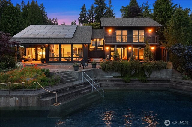 9707 SW Quartermaster Dr, Vashon, WA 98070 - back of house with a balcony, roof mounted solar panels, a patio area, and roof with shingles