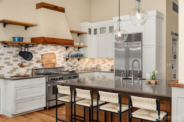9707 SW Quartermaster Dr, Vashon, WA 98070 - kitchen featuring appliances with stainless steel finishes, open shelves, dark countertops, and a kitchen bar
