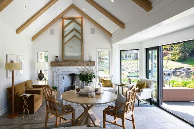 8580 Hunts Point Ln, Hunts Point, WA 98004 - dining room featuring high vaulted ceiling, beam ceiling, a brick fireplace, stone tile floors, and baseboards