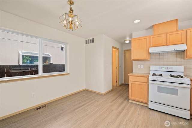 10040 19th Ave SW, Seattle, WA 98146 - kitchen with white gas range, under cabinet range hood, light brown cabinets, light wood finished floors, and a chandelier