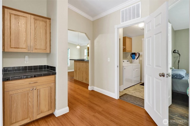 6098 Mt Baker Hwy, Deming, WA 98244 - kitchen with washing machine and dryer, ornamental molding, light wood-type flooring, and light brown cabinets