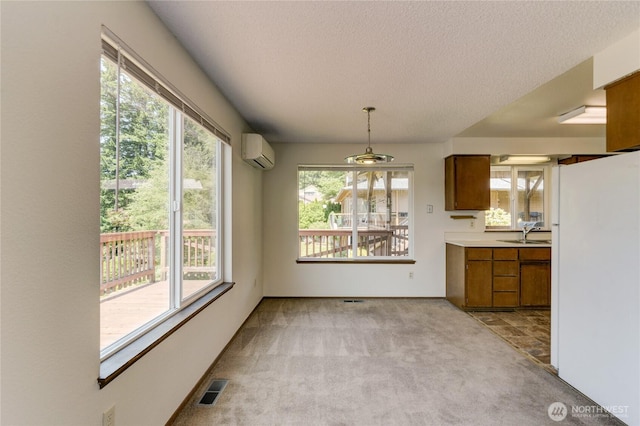 4103 Ward Lake Ct SE, Olympia, WA 98501 - kitchen featuring a wall mounted air conditioner, freestanding refrigerator, brown cabinetry, light colored carpet, and a textured ceiling