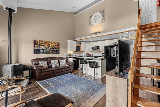 8903 Crescent Bar Rd NW Unit 18, Quincy, WA 98848 - living area featuring a wood stove, stairway, a high ceiling, dark wood-style floors, and recessed lighting