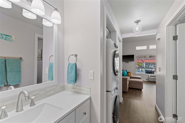 8903 Crescent Bar Rd Unit 158, Quincy, WA 98848 - bathroom featuring stacked washing machine and dryer, vanity, wood finished floors, and a textured ceiling