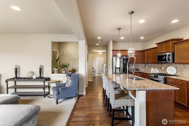 5418 Bennett Ave SE, Auburn, WA 98092 - kitchen with appliances with stainless steel finishes, a sink, a breakfast bar area, light stone counters, and decorative backsplash