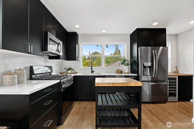 6014 40th Ave NE Unit B, Seattle, WA 98115 - kitchen featuring dark cabinetry, appliances with stainless steel finishes, wooden counters, decorative backsplash, and light wood-style flooring