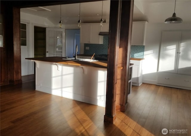 3504 L Pl, Seaview, WA 98644 - kitchen with decorative backsplash, under cabinet range hood, wood finished floors, a breakfast bar area, and white cabinetry