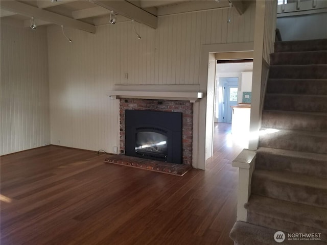3504 L Pl, Seaview, WA 98644 - unfurnished living room featuring wood finished floors, stairway, beamed ceiling, track lighting, and a brick fireplace