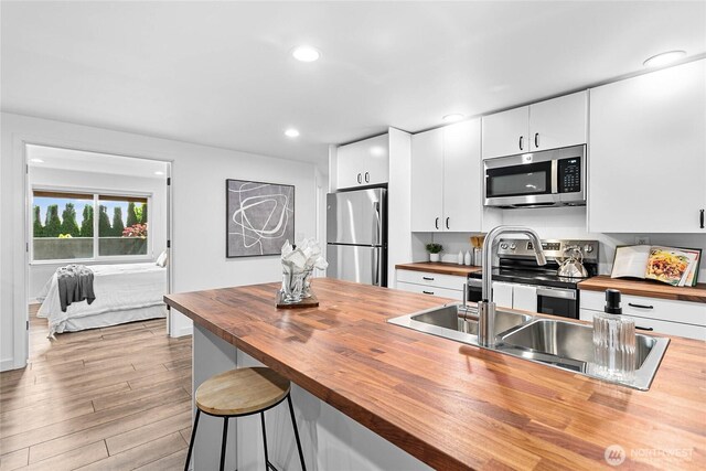 8068 Niska Rd, Blaine, WA 98230 - kitchen with wood counters, appliances with stainless steel finishes, white cabinets, wood finished floors, and recessed lighting