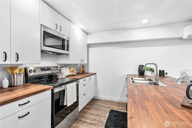 8068 Niska Rd, Blaine, WA 98230 - kitchen featuring butcher block counters, appliances with stainless steel finishes, dark wood-style flooring, white cabinetry, and recessed lighting