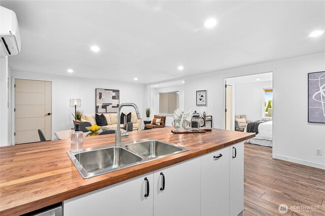 8068 Niska Rd, Blaine, WA 98230 - kitchen featuring wooden counters, a wall mounted air conditioner, open floor plan, dark wood finished floors, and white cabinets