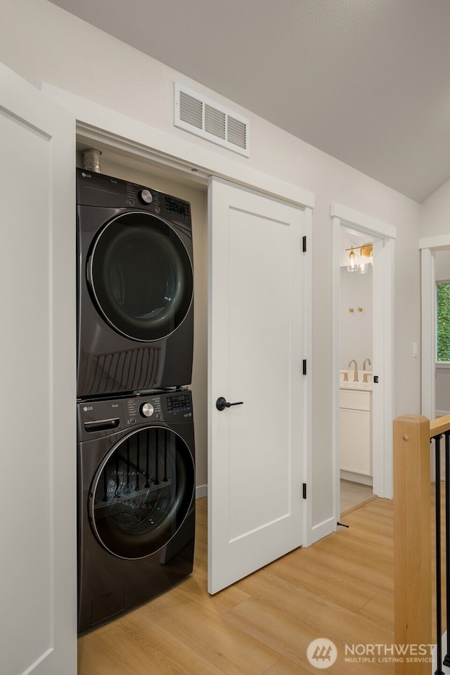 10602 NE 137th Pl, Kirkland, WA 98033 - laundry room with stacked washer / dryer and light wood finished floors