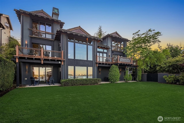 1104 Lakeside Ave S, Seattle, WA 98144 - back of property at dusk with a balcony, a lawn, a chimney, and a patio area