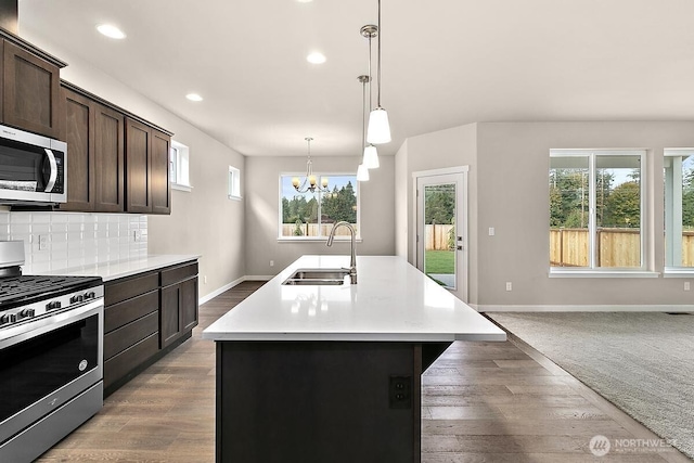 812 Bodie Ct SE, Lacey, WA 98513 - kitchen with appliances with stainless steel finishes, dark brown cabinets, an island with sink, light countertops, and recessed lighting